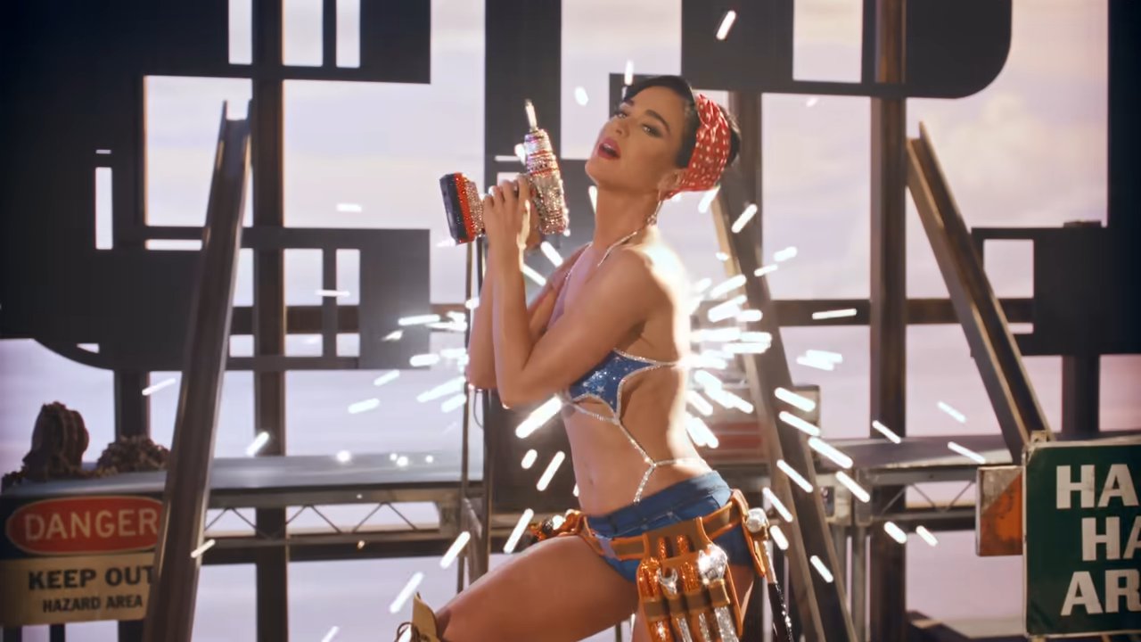 Katy Perry with a drill in a music video dressed as a builder 