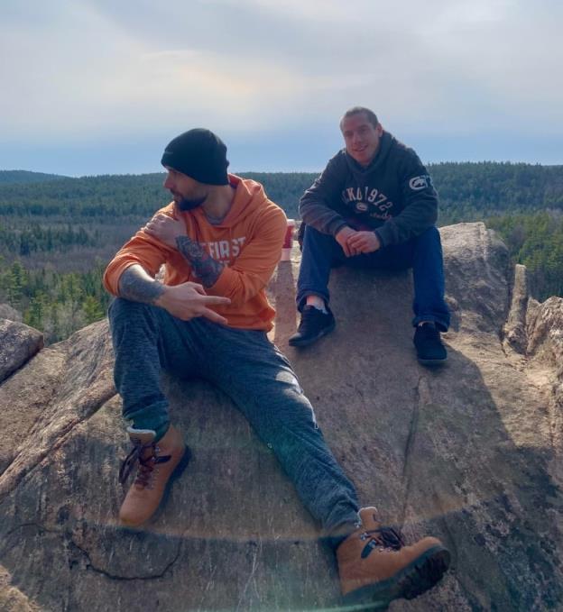 Two men sit on a rock overlooking a canyon