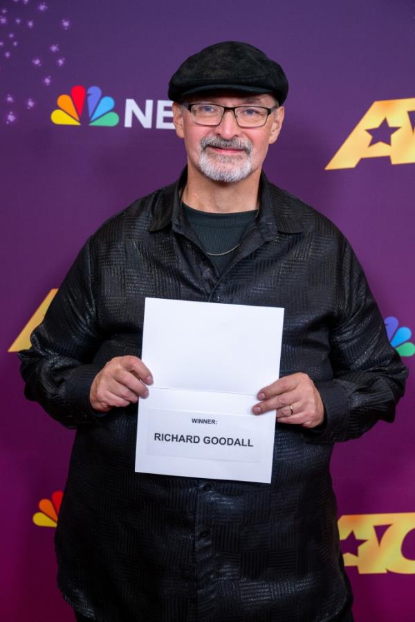 Richard Goodall, winner of America's Got Talent Season 19, walking on the winner's red carpet, holding a piece of paper